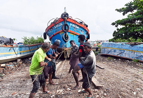Fishermen hauling boats ashore to safe places at Kozhikode Puthiyappa Harbour. 