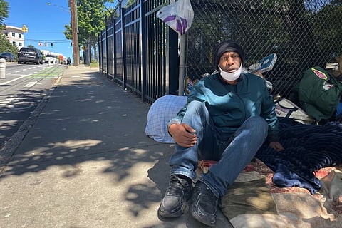 Tomy Elam sits on a sidewalk with his belongings in downtown Atlanta on Thursday, May 14, 2026.