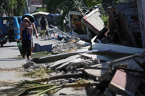 Residents walk past debris from a damaged building in General Santos, southern Philippines, Thursday, June 11, 2026, following Monday's powerful earthquake. 