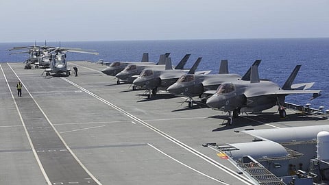 Military personnel inspect US and British jets as they participate in the NATO Steadfast Defender 2021 exercise on board the aircraft carrier HMS Queen Elizabeth off the coast of Portugal.