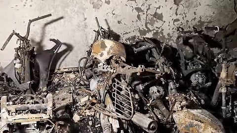 Charred remains of two-wheelers and bicycles are seen after a fire broke out in a five-storey residential building at Tughlakabad Extension area, in New Delhi, Friday, June 12, 2026.