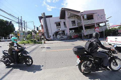 People on motorcycles pass by a collapsed structure after an earthquake in General Santos, Philippines on Monday, June 8, 2026.