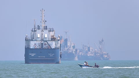 A small motorboat passes anchored vessels in the Strait of Hormuz off Bandar Abbas, Iran, Thursday, June 11, 2026.