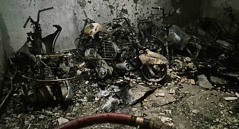 Charred remains of two-wheelers and bicycles are seen after a fire broke out in a five-storey residential building at Tughlakabad Extension area, in New Delhi, Friday, June 12, 2026.