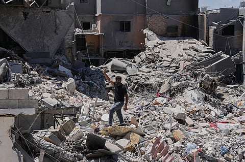 A man flashes the victory sign,as he stands on the rubble of destroyed houses that were recently hit in an Israeli airstrike in the southern port city of Tyre, Friday, June 12, 2026. 