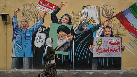 A woman walks past a pro-government mural in downtown Tehran, Iran, Sunday, May 17, 2026.