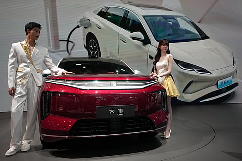 Models stand next to a latest EV car from Chinese automaker BYD showcased at the Auto China 2026, in Beijing, April 25, 2026
