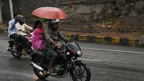 People protecting themselves with umbrella during a light drizzle in Hyderabad on saturday evening.