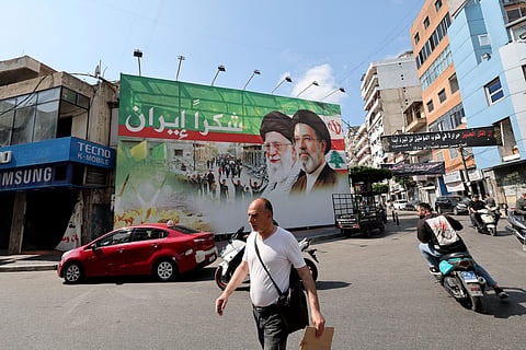A man walks past a giant billboard depicting the late Iranian leader Ayatollah Ali Khamenei (C), and his son the Iranian Supreme Leader Ayatollah Mojtaba Khamenei, with Arabic writing that reads: "Thank you Iran", in Dahiyeh, Beirut's southern suburbs on June 15, 2026.