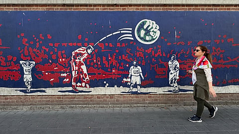 A woman walks past a mural depicting Iranian midfielder Hamid Estili scoring against the United States during their 1998 FIFA World Cup match, which Iran won 2-1, on the wall of the former U.S. Embassy, now an anti-American museum, in Tehran, Iran, Friday, June 12, 2026