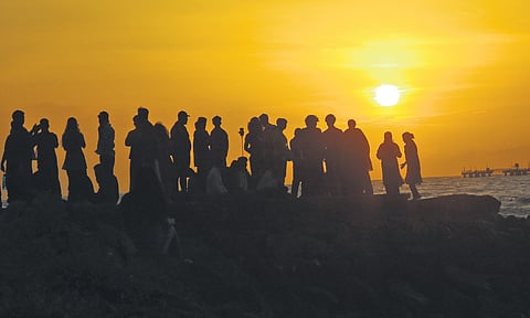 With the sky temporarily clearing, visitors gather to enjoy a sunset at Fort Kochi beach on Tuesday.