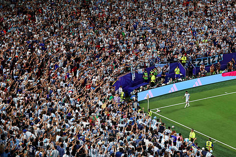 Lionel Messi walks to take a corner with thousands of fan watching on