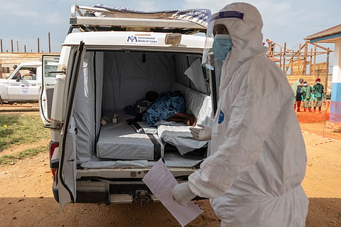 A paramedic stands by a suspected Ebola patient lying in an ambulance at a treatment center in Bunia, Congo.