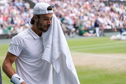 Lorenzo Musetti of Italy wipes the sweat from his face during his semifinal match against Novak Djokovic.