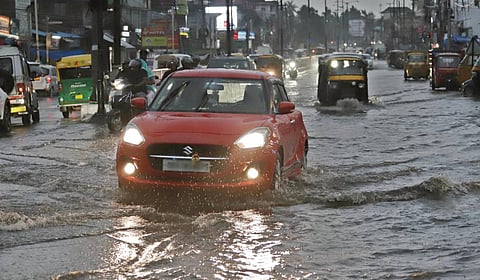 Vehicles struggle to navigate waterlogged Cuttack road following the rain in Bhubaneswar on Friday.