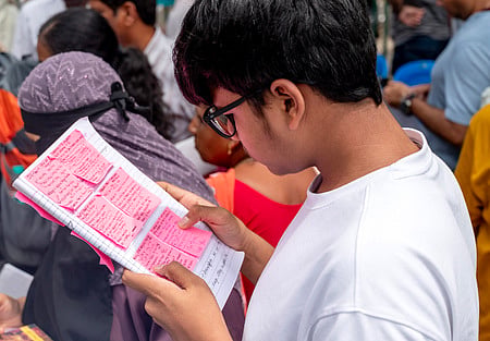 A medical aspirant going through his notes as he waits in line to enter his NEET exam centre.