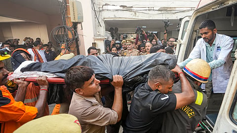 Rescue personnel carry a victim's body into an ambulance after a fire broke out at a commercial building in Aliganj, Lucknow, Uttar Pradesh, Monday, June 22, 2026. 