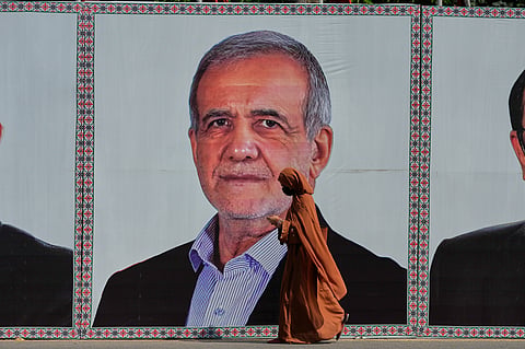 A woman walks past a welcoming billboard featuring Iranian President Masoud Pezeshkian along a roadside in Islamabad, Pakistan, Tuesday, June 23, 2026. 