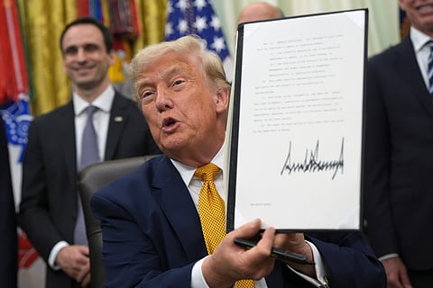 President Donald Trump holds up a signed executive order about quantum computing, in the Oval Office of the White House, Monday, June 22, 2026, in Washington.