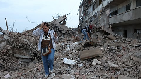 Residents walk among the rubble of building damaged in earthquakes the previous day in Catia La Mar, Venezuela on Thursday