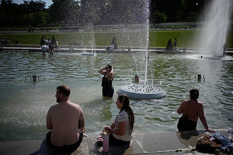 People cool off at Trocadero fountain near the Eiffel Tower during a heat wave in Paris, Wednesday, June 24, 2026. 
