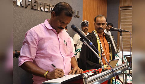 Mannanthala councillor Chempazhanthy Udayan signs the register after taking the oath during the re-swearing-in ceremony of BJP councillors at the Thiruvananthapuram Corporation Conference Hall on Wednesday, as Mayor VV Rajesh looks on.