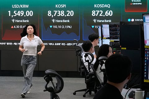 A currency trader passes by a screen showing the Korea Composite Stock Price Index (KOSPI) and the foreign exchange rate between US dollar and South Korean won at the foreign exchange dealing room of the Hana Bank headquarters in Seoul, South Korea, Friday, June 26, 2026. 