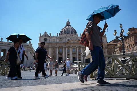 People shade from the sun under umbrellas as they walk through St. Peter's Square at the Vatican, Thursday, June 25, 2026.