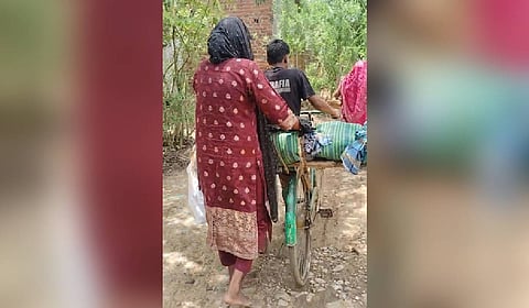 The woman’s body being carried behind a bicycle by her family.
