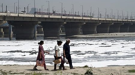 Thick, toxic foam drifts across the surface of the Yamuna River at Kalindi Kunj ghats, caused by untreated sewage and industrial pollution.