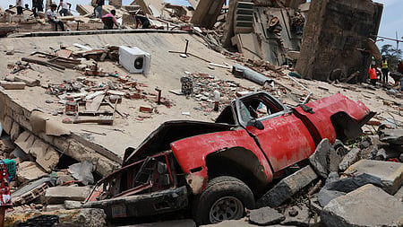 A vehicle is crushed at a building that collapsed after earthquakes struck La Guaira, Venezuela, Thursday, June 25, 2026. 