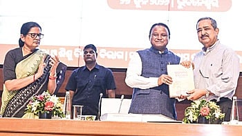 Chief Minister Majhi presenting the vision document to Lahiri as deputy CM Pravati Parida looks on.
