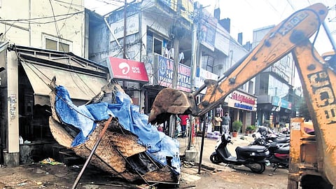 A bulldozer clear a footpath of encroachment in Cyberabad on Saturday.