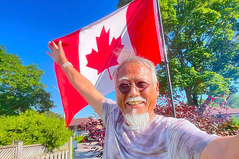 In this photo released by Dong Guangping, he poses for a photo with the Canadian flag after arriving in Toronto, Canada on June 27, 2026.