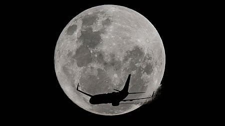 An aircraft passes in front of the full moon, known as the 'Strawberry Moon' over Coogee Beach in Sydney on June 11, 2025.