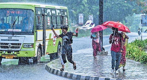 A transwoman jumps with joy while enjoying the rain as other passersby look on, at Rajmahal Square in Bhubaneswar on Tuesday 