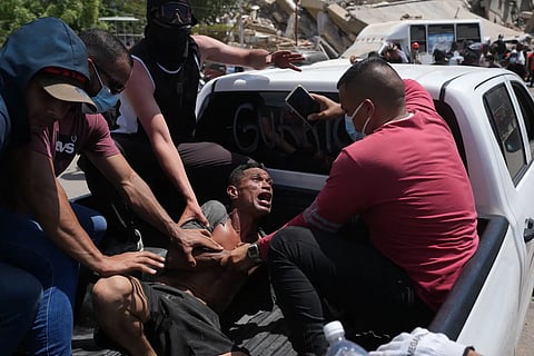 Residents transport a man rescued from the rubble three days after earthquakes struck, in La Guaira, Venezuela, Saturday, June 27, 2026.