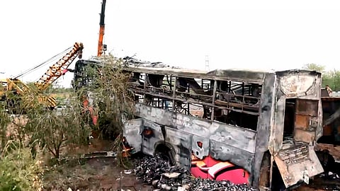 Locals gather near the charred remains of a passenger bus after it rammed into a truck and caught fire on the Delhi-Mumbai Expressway, near Dhanawda under the Kolwa police station area, killing eight people.