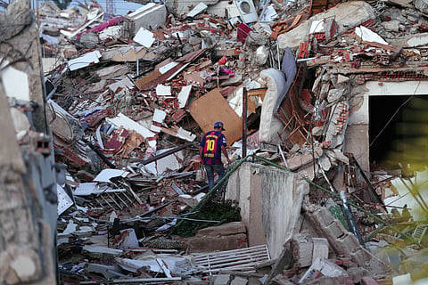A man wearing a Barcelona soccer team jersey searches through earthquake rubble in La Guaira, Venezuela, Wednesday, July 1, 2026.