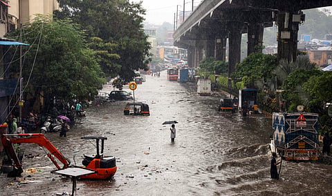 Vehicles and people wade through a waterlogged road following heavy rainfall in Mumbai.