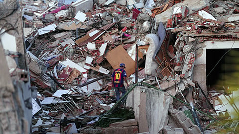 A man wearing a Barcelona soccer team jersey searches through earthquake rubble in La Guaira, Venezuela, Wednesday, July 1, 2026.