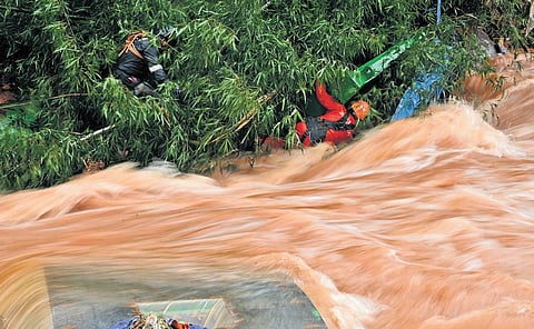 Fire force personnel search for missing persons while the Kalladi river flows in spate following the heavy rain in Wayanad on Wednesday