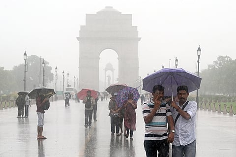 People walk holding umbrellas amid rain at India Gate, in New Delhi on Wednesday.