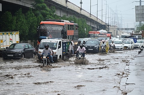 Commuters make their way through a waterlogged area amid rain at Gazipur, in New Delhi on Wednesday.