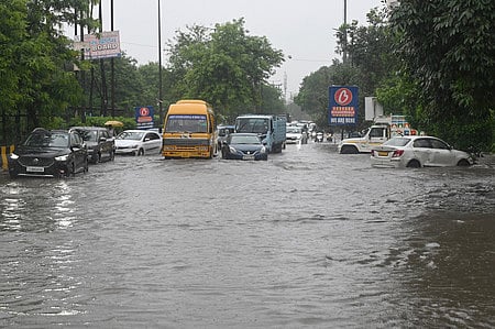 Commuters wade through waterlogged roads in Ghaziabad's Abhay Khand area as the city continues to receive uninteruppted rain since last night, on Thursday