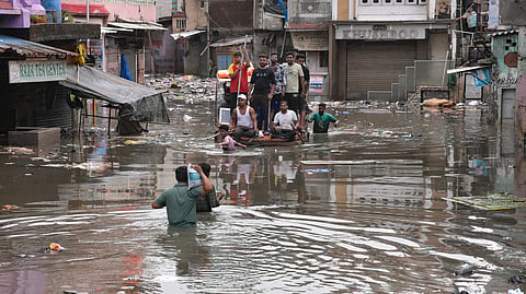 People use a boat to cross a waterlogged area following heavy rain, in Surat.