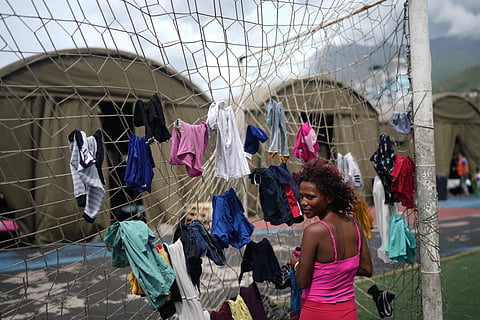 Nataly Mayora hangs clothes to dry on a soccer goal net as she does laundry at a sports center sheltering people displaced by the earthquakes in La Guaira, Venezuela, Thursday, July 9, 2026.
