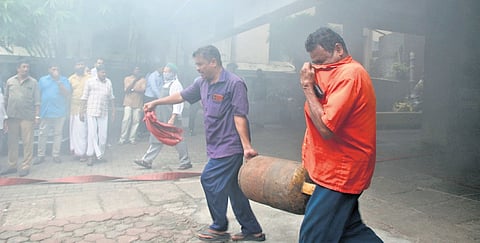 Employees shift a gas cylinder from the kitchen of the hotel that caught fire 
on Friday