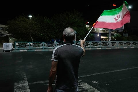 A pro-government demonstrator waves an Iranian flag in a gathering commemorating the late Iranian Supreme Leader Ayatollah Ali Khamenei at a square in Tehran, Iran, Saturday, July 11, 2026. 