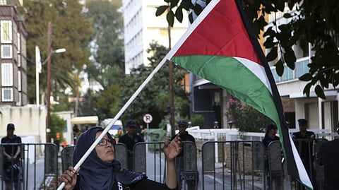 A Palestinian woman holds up the Palestinian flag outside the Israeli embassy.